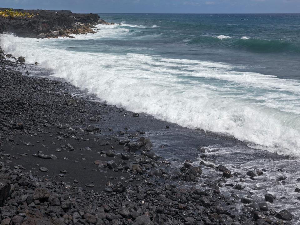 Waves crash on a black sand beach on the Big Island of Hawaii