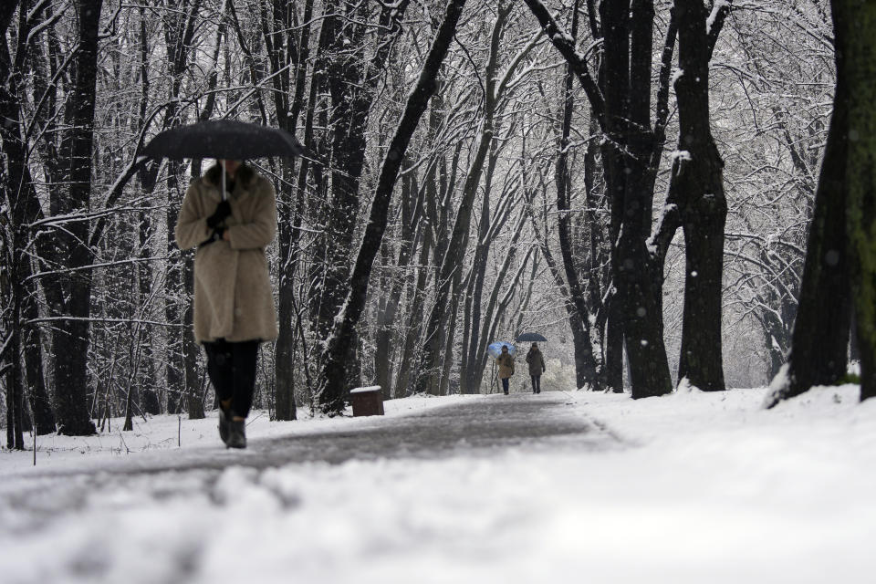 A woman walks through a snow covered park in Belgrade, Serbia, Sunday, Feb. 26, 2023. Serbia and the rest of the region were hit by a sudden weather change this weekend that brought rain and snow after a warm period. (AP Photo/Darko Vojinovic)