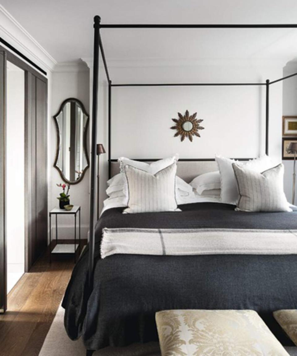 Black and white bedroom with mirror hanging over bedside tables