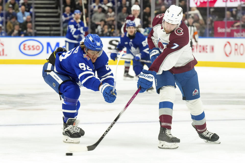 Colorado Avalanche defenseman Devon Toews (7) clears the puck from Toronto Maple Leafs right wing William Nylander (88) during the second period of an NHL hockey game in Toronto, Saturday, Jan. 13, 2024. (Chris Young/The Canadian Press via AP)