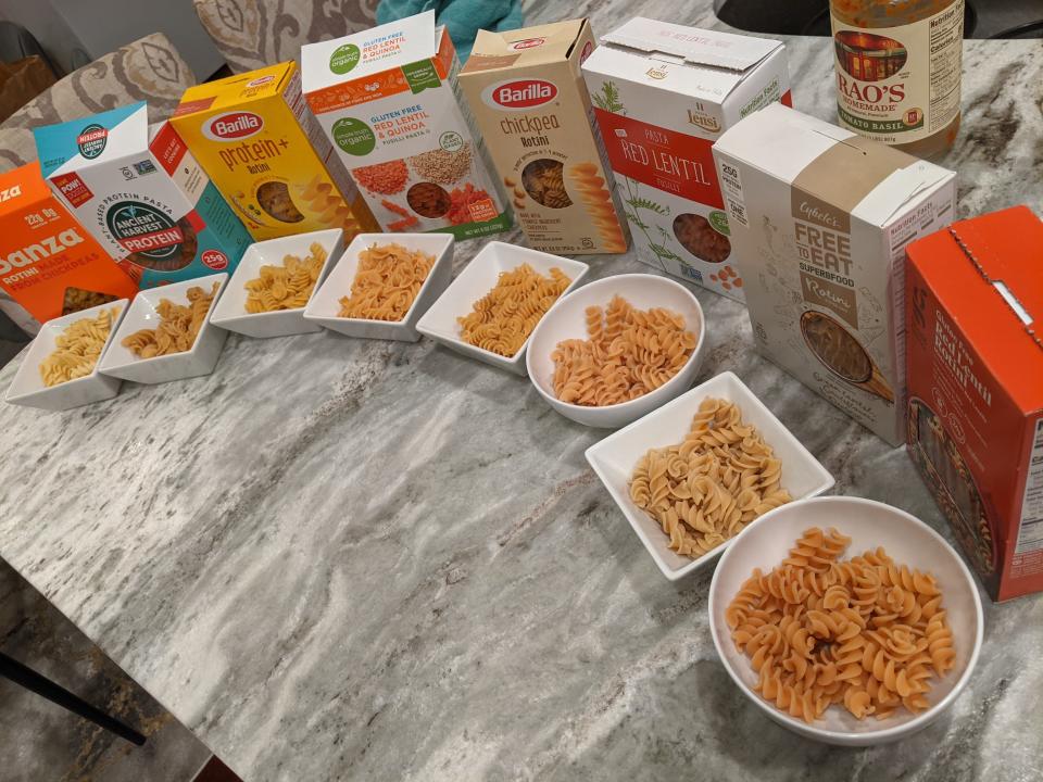 all 8 of the protein pasta brands lined up in a semi-circle on a kitchen counter