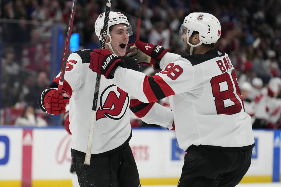 New Jersey Devils left wing Nolan Foote (25) celebrates his goal against the Tampa Bay Lightning with defenseman Kevin Bahl (88) during the.third period of an NHL hockey game Sunday, March 19, 2023, in Tampa, Fla. (AP Photo/Chris O'Meara)