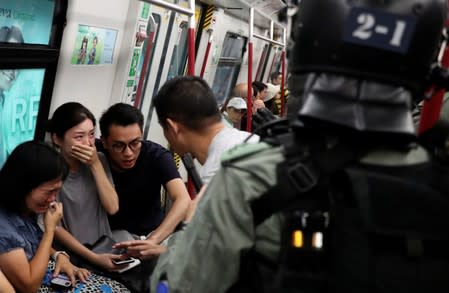 Commuters react as police officers looking for protestors raid a metro train, in Hong Kong