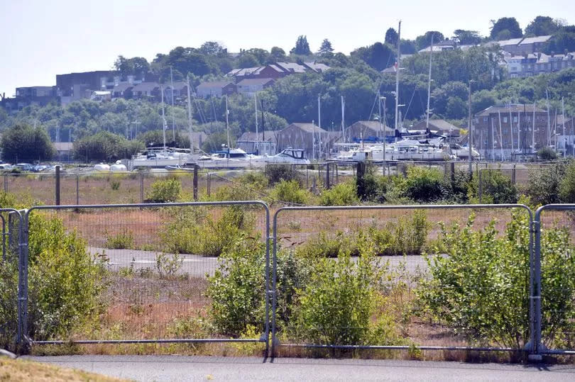 Fenced-off area of Cardiff Pointe with yachts visible in background