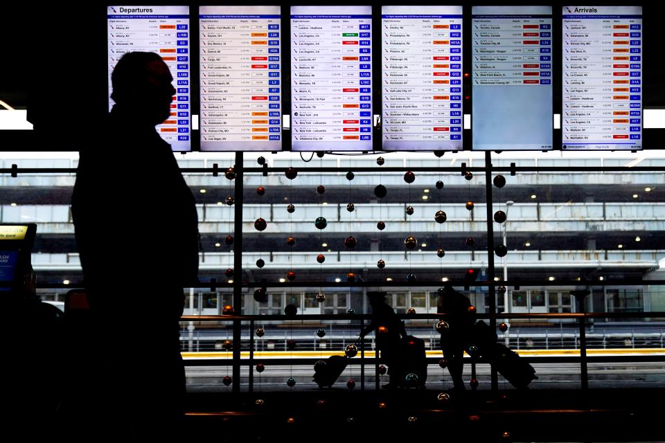 Travelers walk past flight information screens displaying flight status information at O'Hare International Airport in Chicago on Thursday (Copyright 2022 The Associated Press. All rights reserved.)