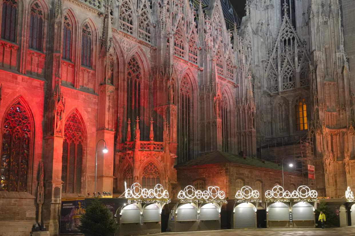 FILE - A man walks by a closed Christmas market, next to the St. Stephen's Cathedral in Vienna, Austria, Nov. 22, 2021. Despite the pandemic inconveniences, stall owners selling ornaments, roasted chestnuts and other holiday-themed items in Frankfurt and other European cities are relieved to be open at all for their first Christmas market in two years, especially with new restrictions taking effect in Germany, Austria and other countries as COVID-19 infections hit record highs. (AP Photo/Vadim Ghirda, File)