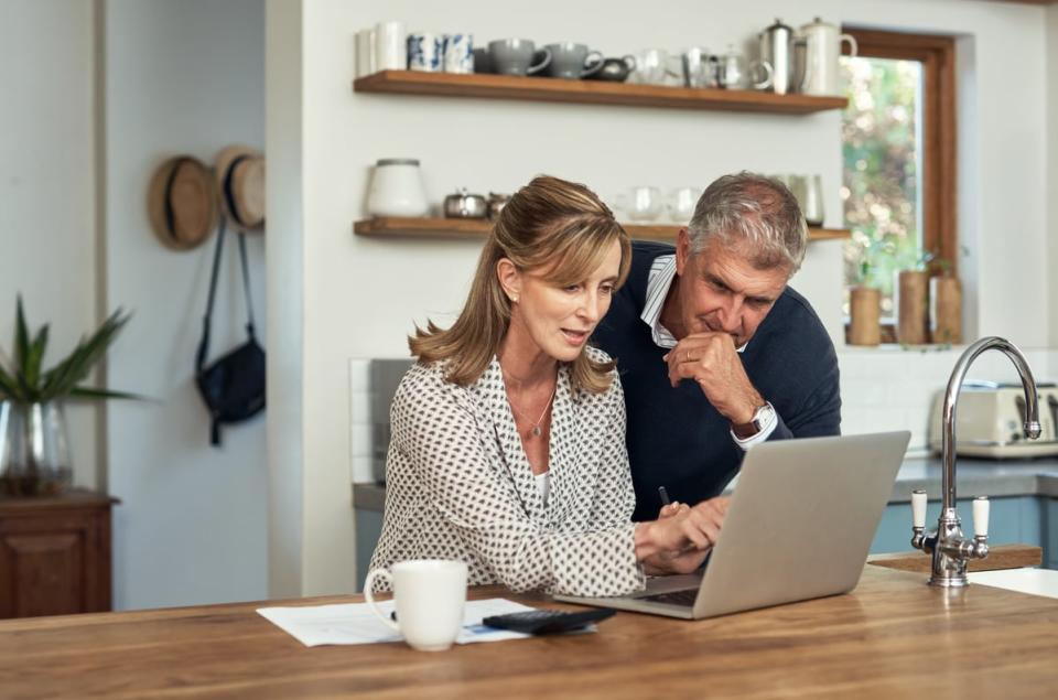 Two people sitting at a table and discussing what's on a computer screen. 