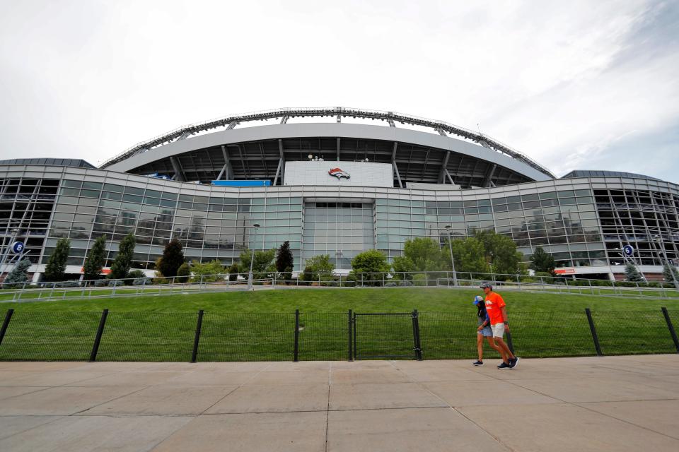 Fans pass by the east side of Mile High Stadium before an NFL preseason football game between the Arizona Cardinals and the Denver Broncos in 2019.