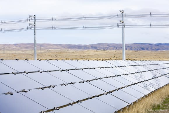 First Solar utility scale installation in a field with power lines in the background.