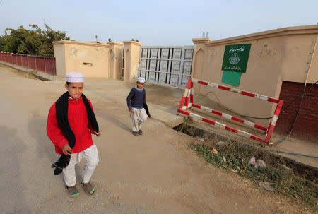 Boys walk past the main gate of Madrasa Hudaybiya, previously run by the Islamic charity organisation Jamaat-ud-Dawa (JuD), in Rawalpindi, Pakistan February 15, 2018. Picture taken February 15, 2018. REUTERS/Faisal Mahmood