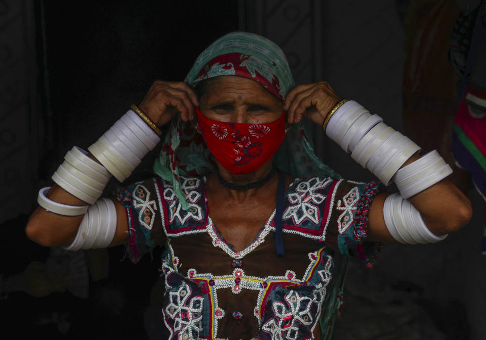 An Indian Lambada tribal woman adjusts her face mask as she stands outside her home in Hyderabad, India, Thursday, May 20, 2021. India has the second-highest coronavirus caseload after the U.S. with more than 25 million confirmed infections. (AP Photo/Mahesh Kumar A.)