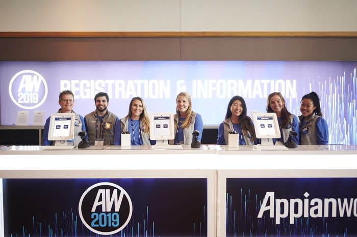 Seven people behind a desk marked Appianworld 2019.