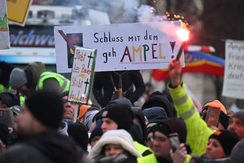 A Bengalo burns during the farmers rally in front of the Brandenburg Gate. The protests are directed against planned subsidy cuts by the federal government, including for agricultural diesel. Sebastian Christoph Gollnow/dpa