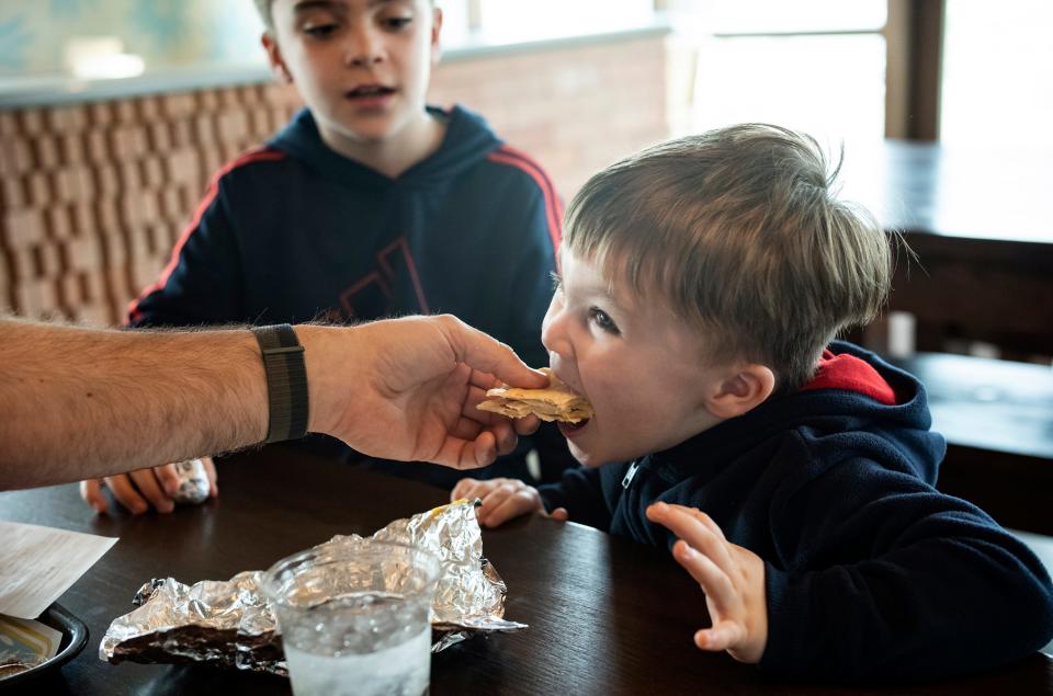 Dane Frazier, 3, takes a bite of a quesadilla held by his father, Jeff, as his brother, Cage, 8, looks on last year during lunch at Taco Ranch on P. Terry's Giving Back Day for Season for Caring.