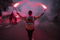 A striking railway worker holds flares during a demonstration in Marseille, southern France, Friday, Jan. 24, 2020. French unions are holding last-ditch strikes and protests around the country Friday as the government unveils a divisive bill redesigning the national retirement system. (AP Photo/Daniel Cole)