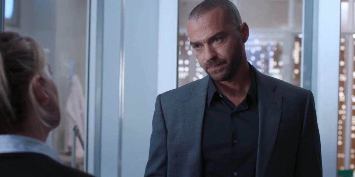 jesse williams as dr jackson avery in grey's anatomy season 21, wearing a black shirt underneath a grey jacket and looking very serious