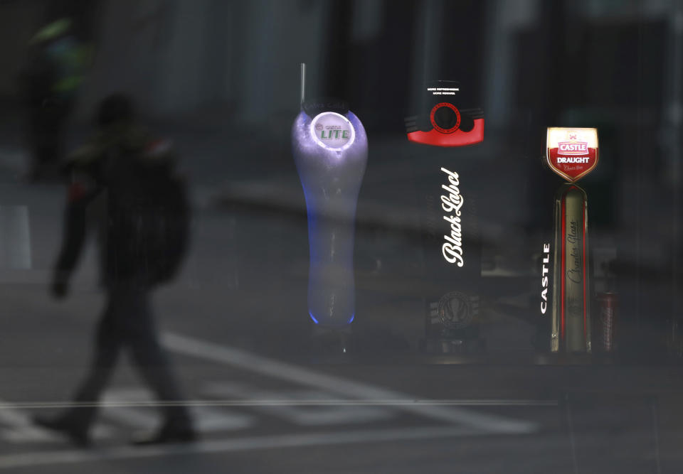 FILE - In this May 7, 2020, file photo, beer taps of South African Brewery brands are seen through the window of a closed bar in Cape Town, South Africa. A bootlegging culture has sprung up across South Africa in response to the government's nearly 8-week-old ban on the sale of cigarettes and alcohol. (AP Photo/Nardus Engelbrecht, File)