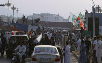 Supporters of Pakistan’s defiant former Prime Minister Imran Khan stand on shipping containers after removing them to open a road during an anti-government rally in Islamabad, Pakistan, Thursday, May 26, 2022. Khan early Thursday warned Pakistan's government to set new elections in the next six days or he will again march on the capital along with 3 million people. (AP Photo/Anjum Naveed)