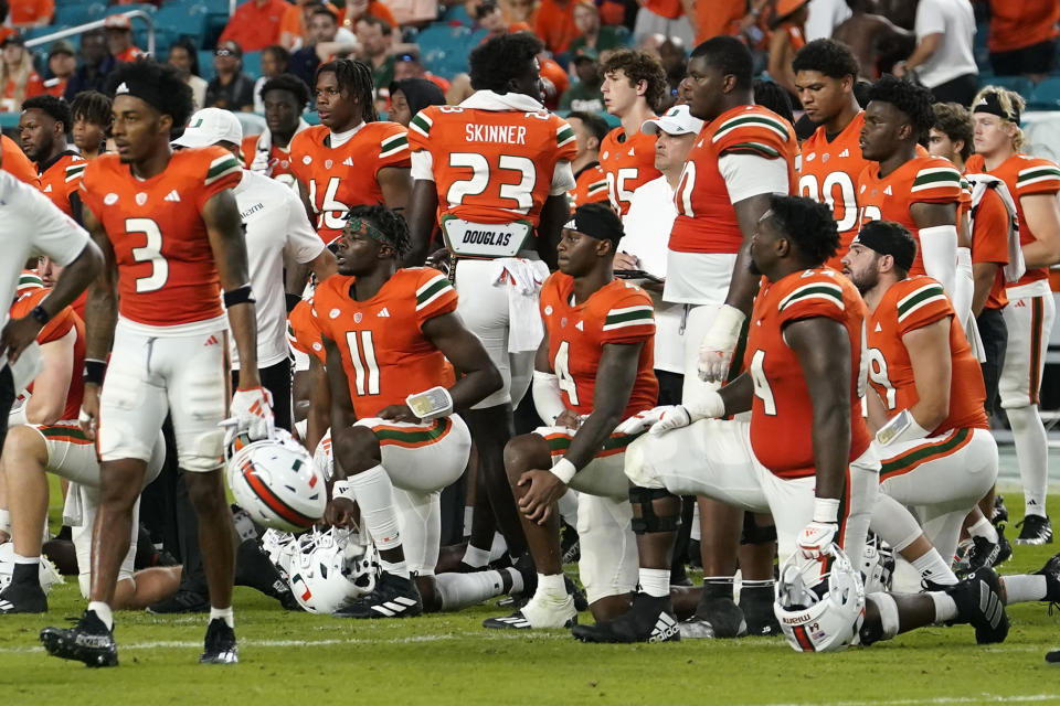Miami players stand on the field as safety Kamren Kinchens lies on the field after an injury during the second half of an NCAA college football game Saturday against Texas A&M, Sept. 9, 2023, in Miami Gardens, Fla. (AP Photo/Lynne Sladky)