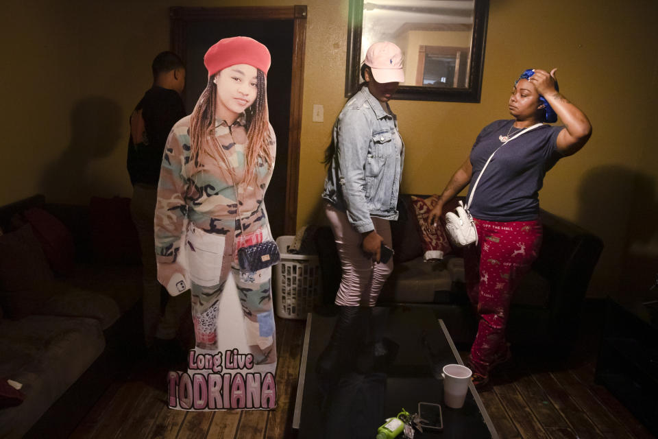 FILE - A cutout of Todriana Peters stands in her living room with her cousin Brione Rogers and mother Katrina Lambert in New Orleans, Thursday, July 8, 2021. Three men have pleaded guilty in connection with a summer shooting that left the 12-year-old New Orleans girl dead and outraged a city already struggling with a rise in murders. The Times-Picayune/The New Orleans Advocate reported that the parents of Todriana Peters were in the courtroom Wednesday, Oct. 27, 2021 when the three men pleaded guilty. One man, Pernell Young, admitted to opening fire during the May 30 shooting outside a graduation party while prosecutors said the other two _ 18-year-old Marcus Venible, and 19-year-old Tyrese Riley _ were not shooters. (AP Photo/Sophia Germer, file)