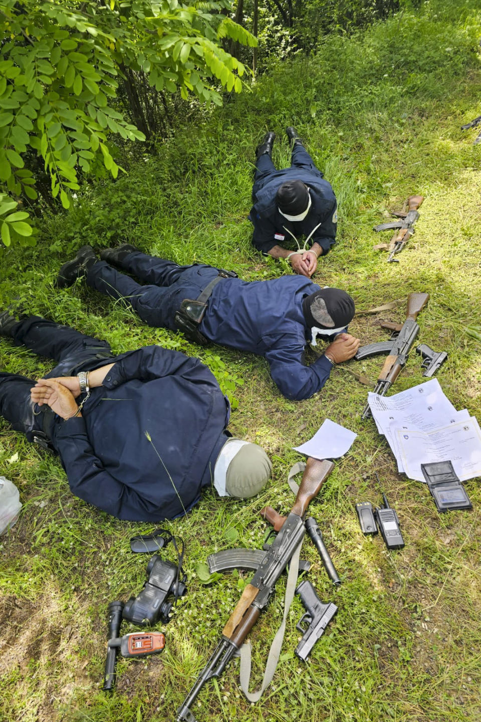 In this photo provided by the Serbian Ministry of Interior, a three Kosovo police officers captured by Serbian police officers lying face down on a field, on Wednesday, June 14, 2023. Serbian authorities said Wednesday they have captured three "fully armed" Kosovo police officers inside Serbia near their mutual border, while Kosovo police said they have likely been "kidnapped" on Kosovo territory as they patrolled the area. (Serbian Ministry of Interior via AP)