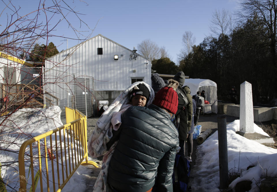 Haitian and Afghani asylum seekers illegally cross into Canada where police took them into custody at the non-official Roxham Road border crossing north of Champlain, New York, on Friday, March 24, 2023. A new US-Canadian migration agreement closes a loophole that has allowed migrants who enter Canada away from official border posts to stay in the country while awaiting an asylum decision. (AP Photo/Hasan Jamali)