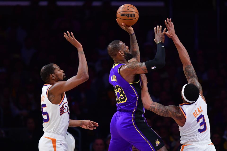 Los Angeles Lakers forward LeBron James (23) shoots against Phoenix Suns guard Bradley Beal (3) and forward Kevin Durant (35) during the first half at Crypto.com Arena.