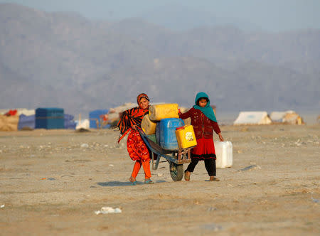 Afghan refugee girls carry drinking water in containers at a refugee camp on the outskirts of Jalalabad, Afghanistan, February 12, 2017. REUTERS/Parwiz