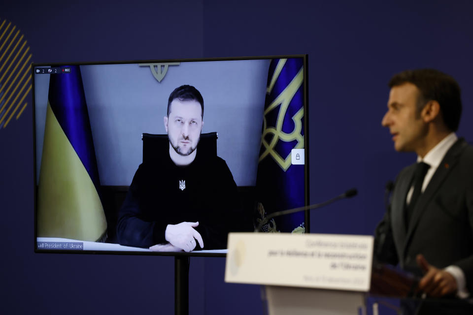 El presidente francés Emmanuel Macron pronuncia un discurso mientras su homólogo ucraniano Volodymyr Zelenskyy escucha en una videollamada, durante una conferencia en París, el martes 13 de diciembre de 2022. (Ludovic Marin, Pool vía AP)