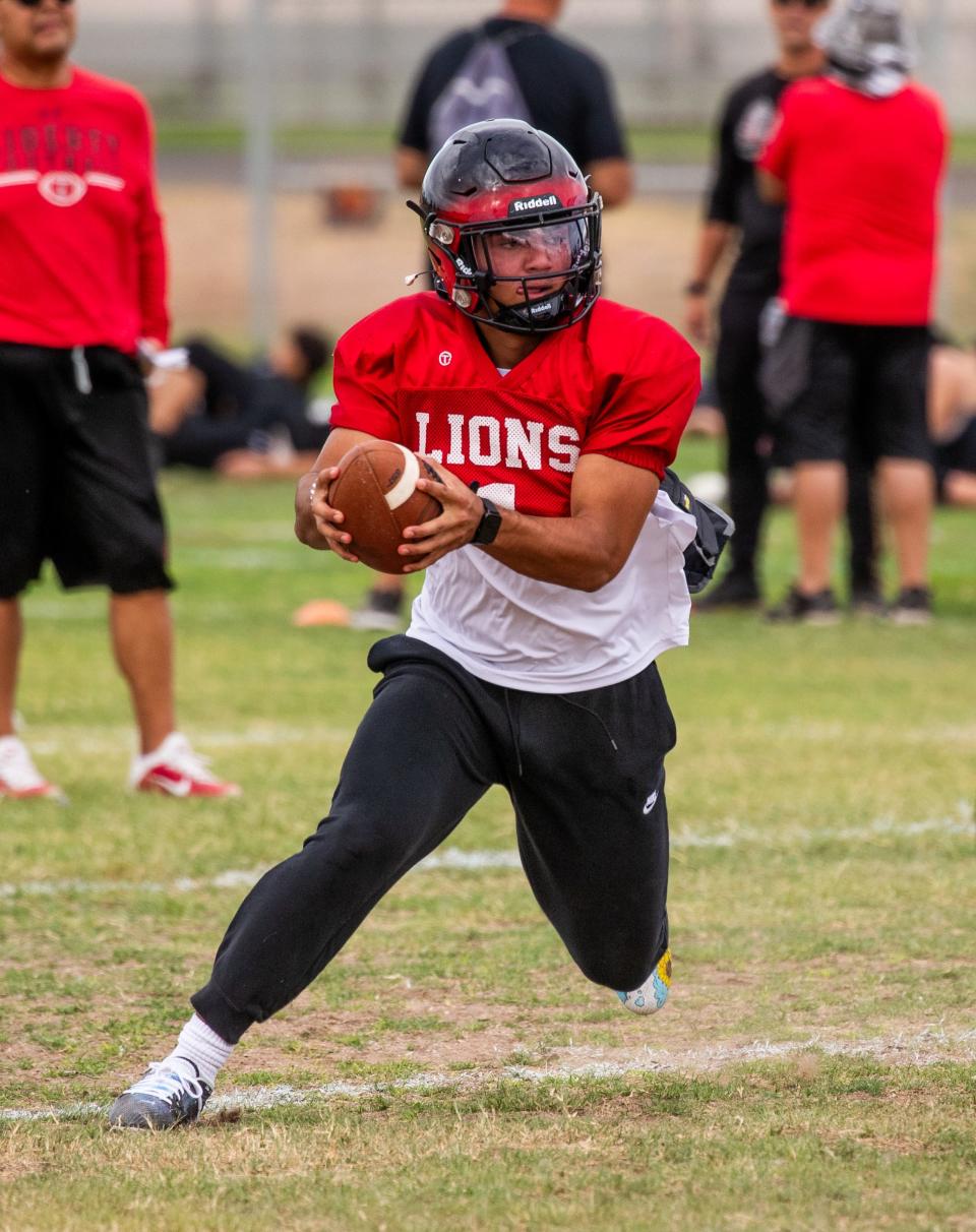 Liberty High School quarterback Navi Bruzon runs with the ball during practice at the Liberty High School football practice field in Peoria on Aug. 21, 2023.