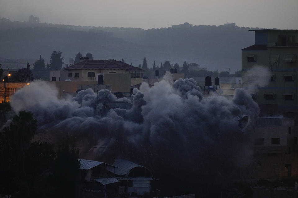 Israeli troops blow up the house of Palestinian militant Diaa Hamarsheh, which is covered by the smoke, in the West Bank village of Yabed, Thursday, June 2, 2022. Hamarsheh was shot and killed by Israeli police after he killed three Israelis and two Ukrainian citizens in a deadly shooting attack in Bnei Brak on March 29, 2021. Israeli officials say the demolitions deter future attacks, while rights groups view it as a form of collective punishment. (AP Photo/Majdi Mohammed)