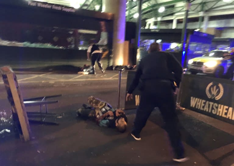 Armed police stand over an attacker shot at the scene Borough Market in central London on June 3, 2017