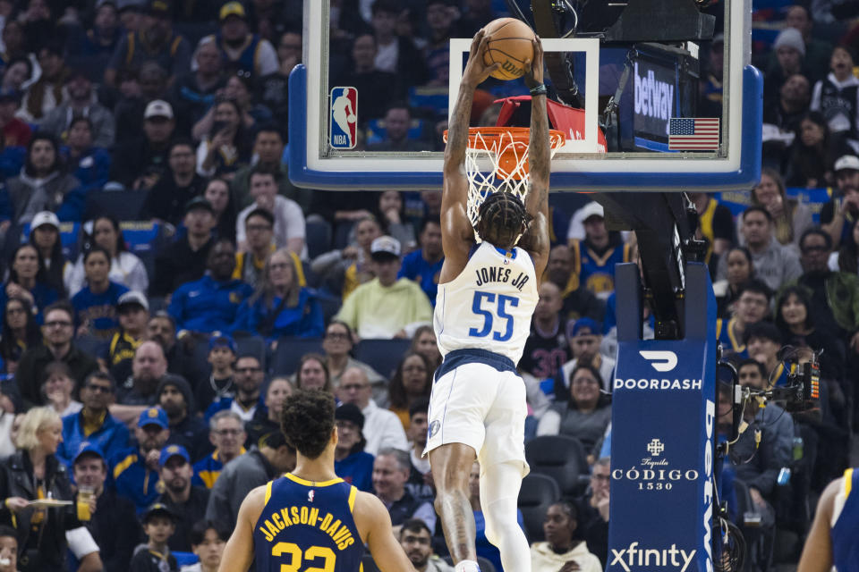 Golden State Warriors forward Trayce Jackson-Davis (32) watches as Dallas Mavericks forward Derrick Jones Jr. (55) dunks during the first half of an NBA basketball game in San Francisco, Saturday, Dec. 30, 2023. (AP Photo/John Hefti)