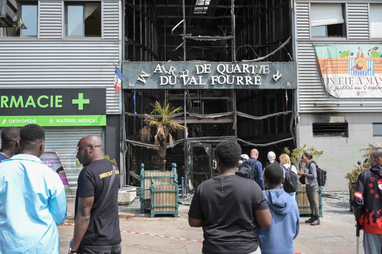 Residentes locales observan junto a la fachada de un anexo quemado del ayuntamiento del barrio Le Val Fouree en Mantes-la-Jolie, un día después del asesinato de un joven de 17 años en Nanterre por un disparo de un oficial de policía tras negarse a cumplir.