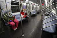 Subway riders wear protective masks and gloves on a sparsely populated car during morning hours due to COVID-19 concerns that are driving down ridership, Thursday, March 19, 2020, in New York. Gov. Andrew Cuomo tightened work-from-home rules Thursday as confirmed cases continued to climb in New York, an expected jump as testing becomes more widespread. But he stressed that roadblocks and martial law for New York City were merely rumors. (AP Photo/John Minchillo)