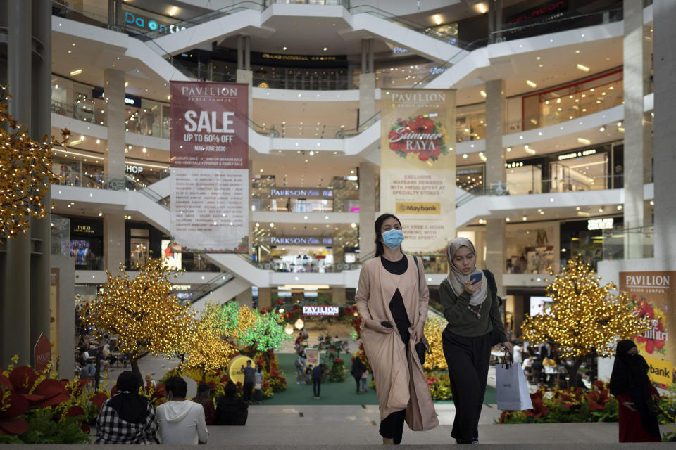 Shoppers wearing face mask walk through a shopping mall in downtown Kuala Lumpur, Malaysia, on Sunday, June 7, 2020. Malaysian government has lifted the conditional movement order (CMCO) and replaced it with a recovery movement control order effective June 10 until Aug. 31. (AP Photo/Vincent Thian)