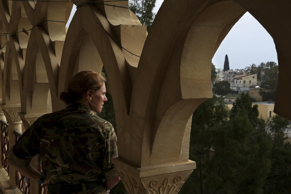 In this Friday, April 19, 2019, photo, a U.N. peacekeeper looks outside from a balcony of a suite room at the Ledra Palace hotel inside the U.N. buffer zone in the divided capital Nicosia, Cyprus. This grand hotel still manages to hold onto a flicker of its old majesty despite the mortal shell craters and bullet holes scarring its sandstone facade. Amid war in the summer of 1974 that cleaved Cyprus along ethnic lines, United Nations peacekeepers took over the Ledra Palace Hotel and instantly turned it into an emblem of the east Mediterranean island nation's division. (AP Photo/Petros Karadjias)