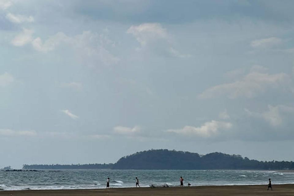 People walk on Kan Thar Yar beach near Gwa township, on 11 May 2023 after cyclone Mocha, the Bay of Bengal’s first cyclone of the year, formed (AFP via Getty Images)