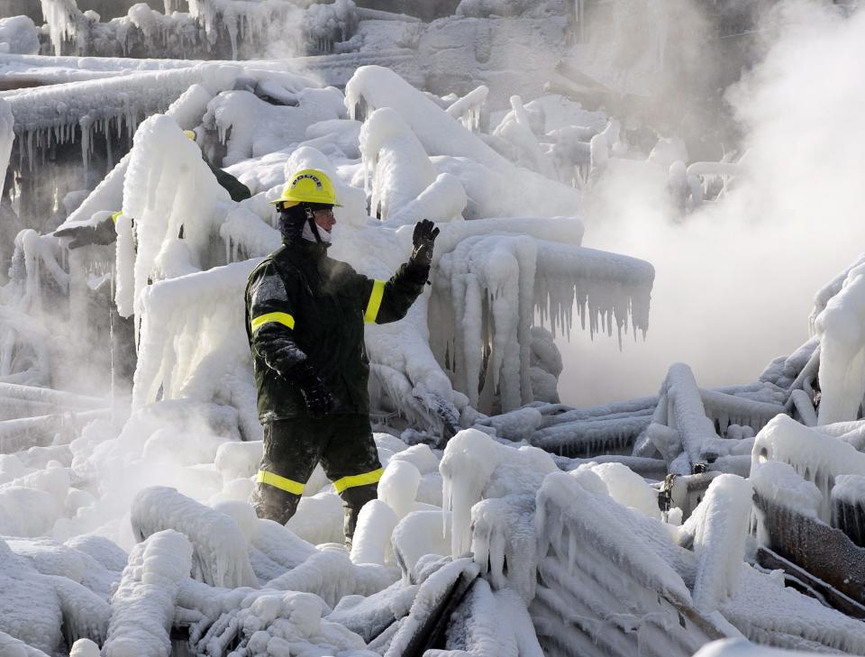 A police investigator signals to colleagues as they search through icy rubble to trying to locate more victims of a fire that destroyed a seniors' residence Friday, Jan. 24, 2014, in L'Isle-Verte, Quebec. Five people are confirmed dead and 30 people are still missing, while with cause of Thursday morning's blaze is unclear police said. Authorities are using steam to melt the ice and to preserve any bodies that are buried. (AP Photo/The Canadian Press, Ryan Remiorz)