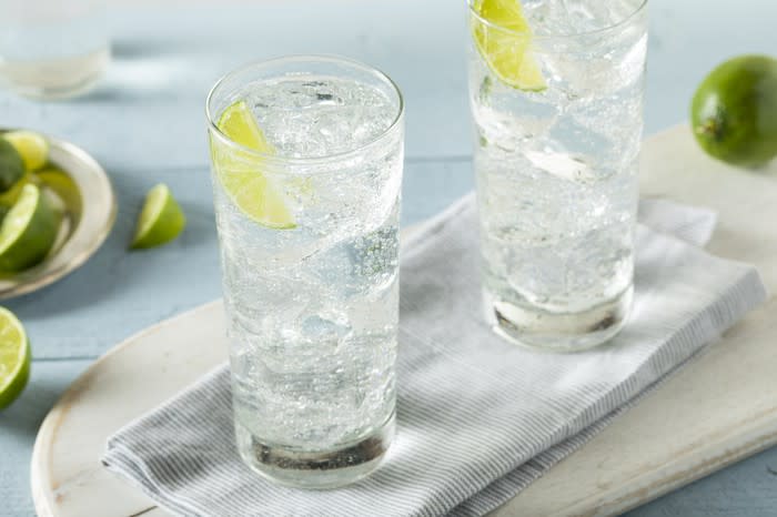 Two glasses of iced sparkling water with lime wedges.