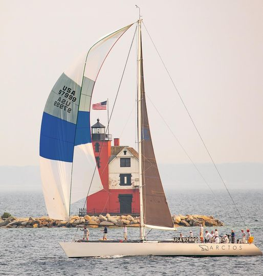 Lynn Kotwicki is among sailors on Arctos crossing the finish line of the Chicago to Mackinac race in July 2021. She is standing beside the 999 in a baseball cap.