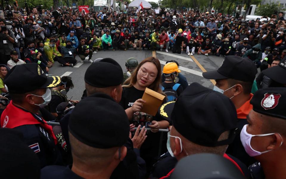 Student leader Panusaya Sithijirawattankul hands over a letter to Royal Guard police, with demands for reforming the monarchy - Reuters