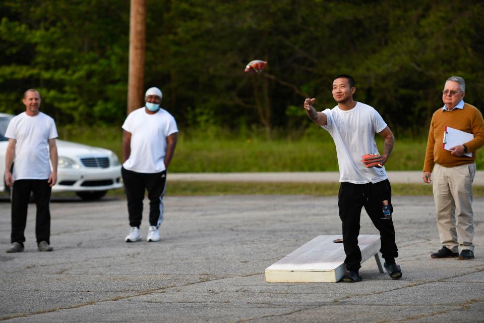 Zhan Cobb, 27, Soteria resident, throws a bean bag while playing corn hole during Soteria House's weekly game night on Friday, May 5, 2023. The house gathers weekly for game night to promote bonding and fun for the residents. Each week the winner of game night is awarded with some kind of prize.