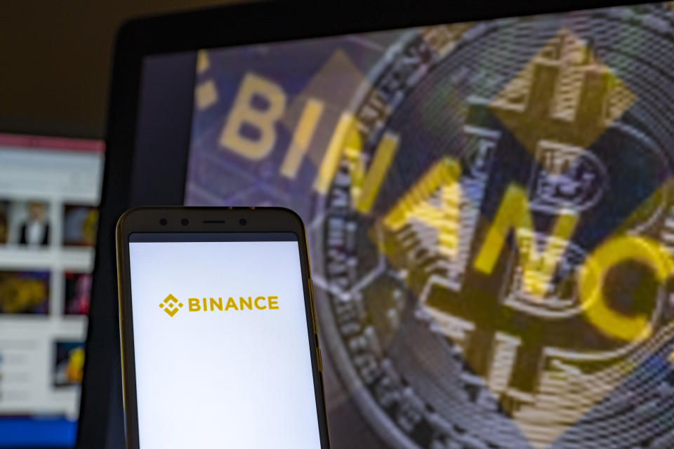 An lllustration of the Binance logo is seen on the screen of a smartphone. 