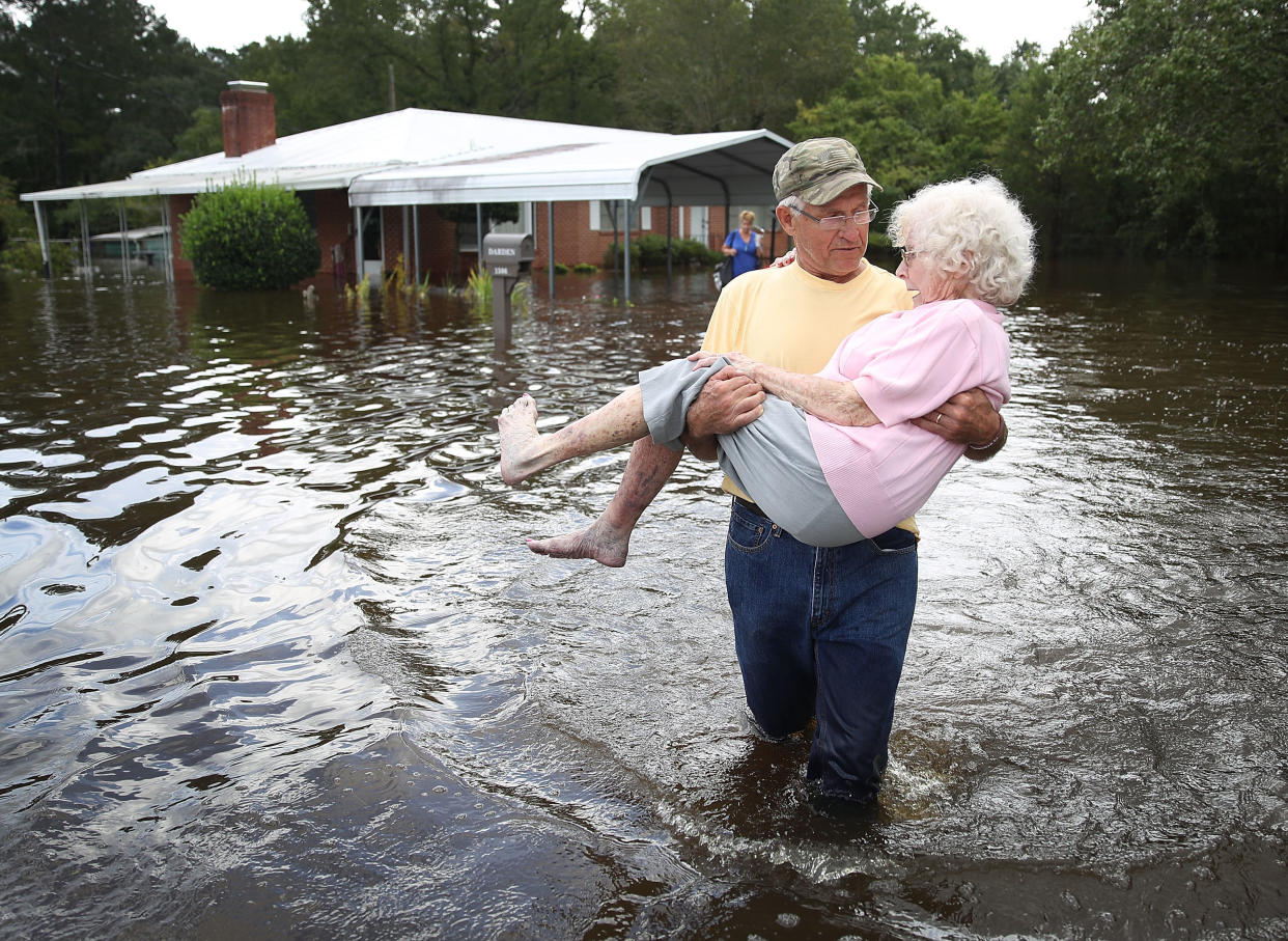 Bob Richling carries Iris Darden as water from the Little River starts to seep into her home on Monday in Spring Lake, North Carolina. (Photo: Joe Raedle/Getty Images)