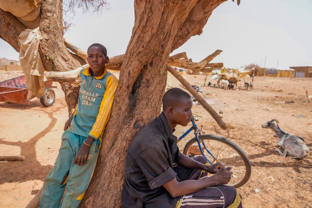 People lean on a tree in Djibo, Burkina Faso, Thursday May 26, 2022. (AP Photo/Sam Mednick)