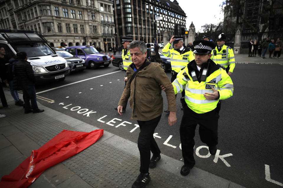 Police remove a climate change protestor from the road during a demonstration on the budget outside Parliament in London, Wednesday, March 11, 2020. Britain's Chancellor of the Exchequer Rishi Sunak will announce the first budget since Britain left the European Union. (AP Photo/Matt Dunham)