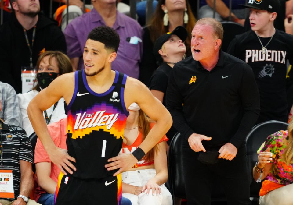 Phoenix Suns owner Robert Sarver, right, reacts alongside guard Devin Booker during Game 2 of the 2021 NBA Finals.