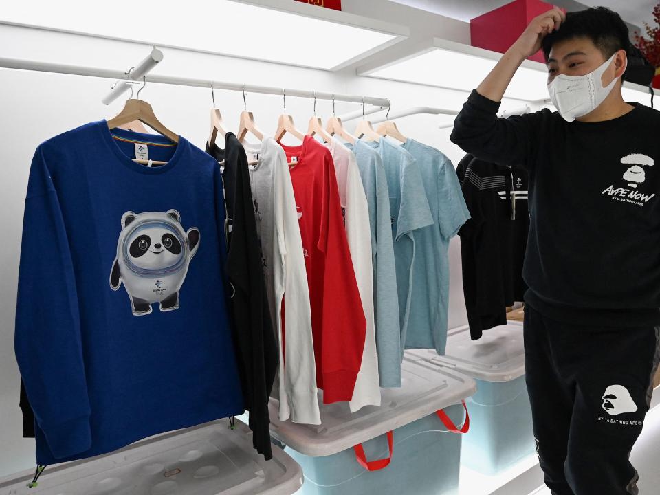 A man walks in front of a shirt featuring Bing Dwen Dwen, the mascot of the 2022 Beijing Winter Olympic Games, at a Beijing Winter Olympics souvenir store at Wangfujing shopping mall complex in Beijing on February, 7, 2022.