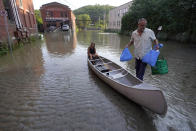 FILE - Jodi Kelly, seated center, practice manager at Stonecliff Veterinary Surgical Center, behind, and her husband Veterinarian Dan Kelly, right, use a canoe to remove surgical supplies from the flood damaged center, Tuesday, July 11, 2023, in Montpelier, Vt. Vermont has become the first state to enact a law requiring fossil fuel companies to pay a share of the damage caused by climate change, Thursday, May 30, 2024 after the state suffered catastrophic summer flooding and damage from other extreme weather. (AP Photo/Steven Senne, File)